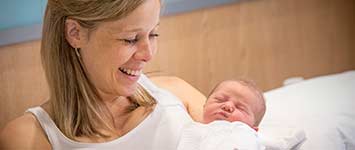 Smiling mother with newborn baby in her arms